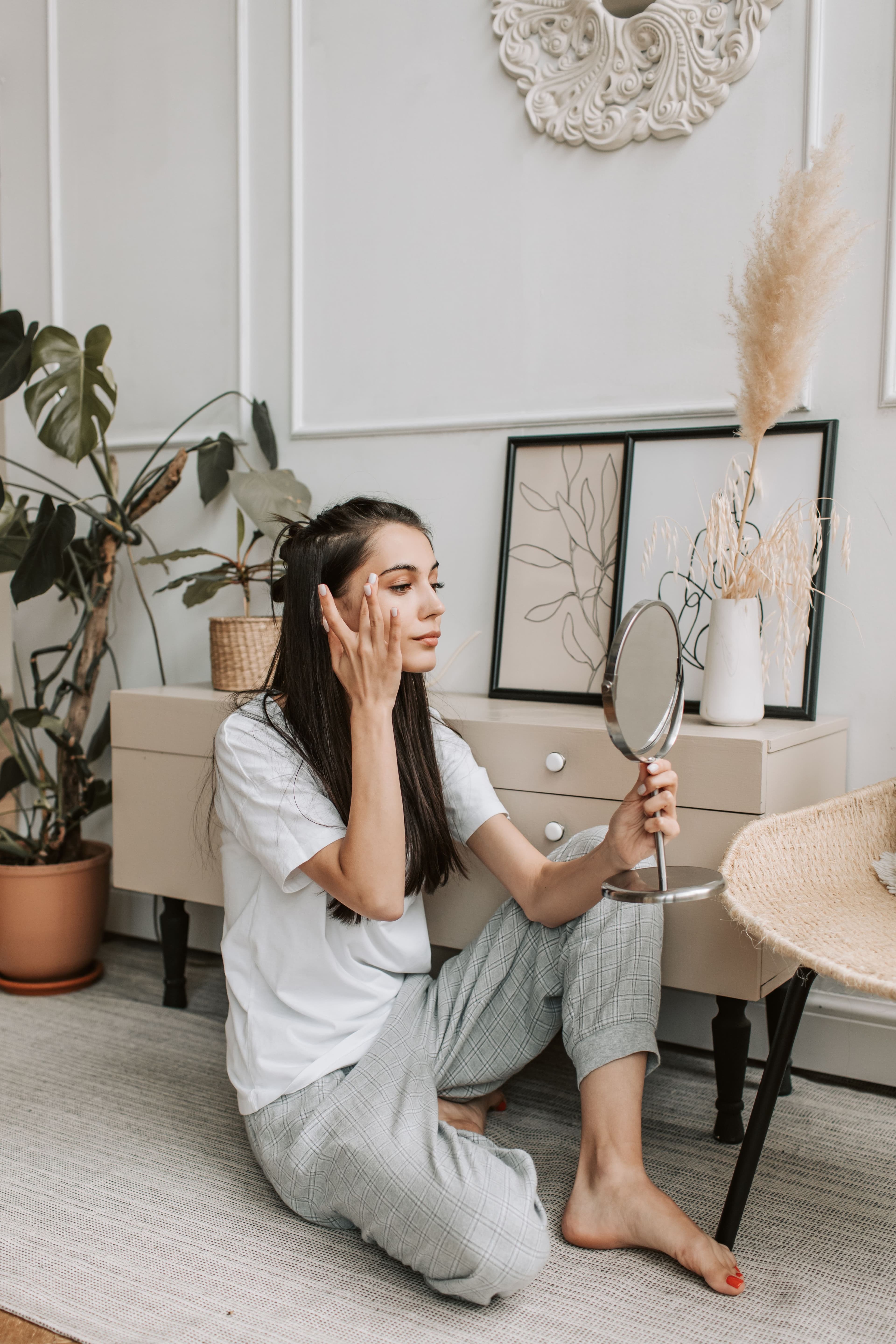Woman looking herself in hand mirror.
