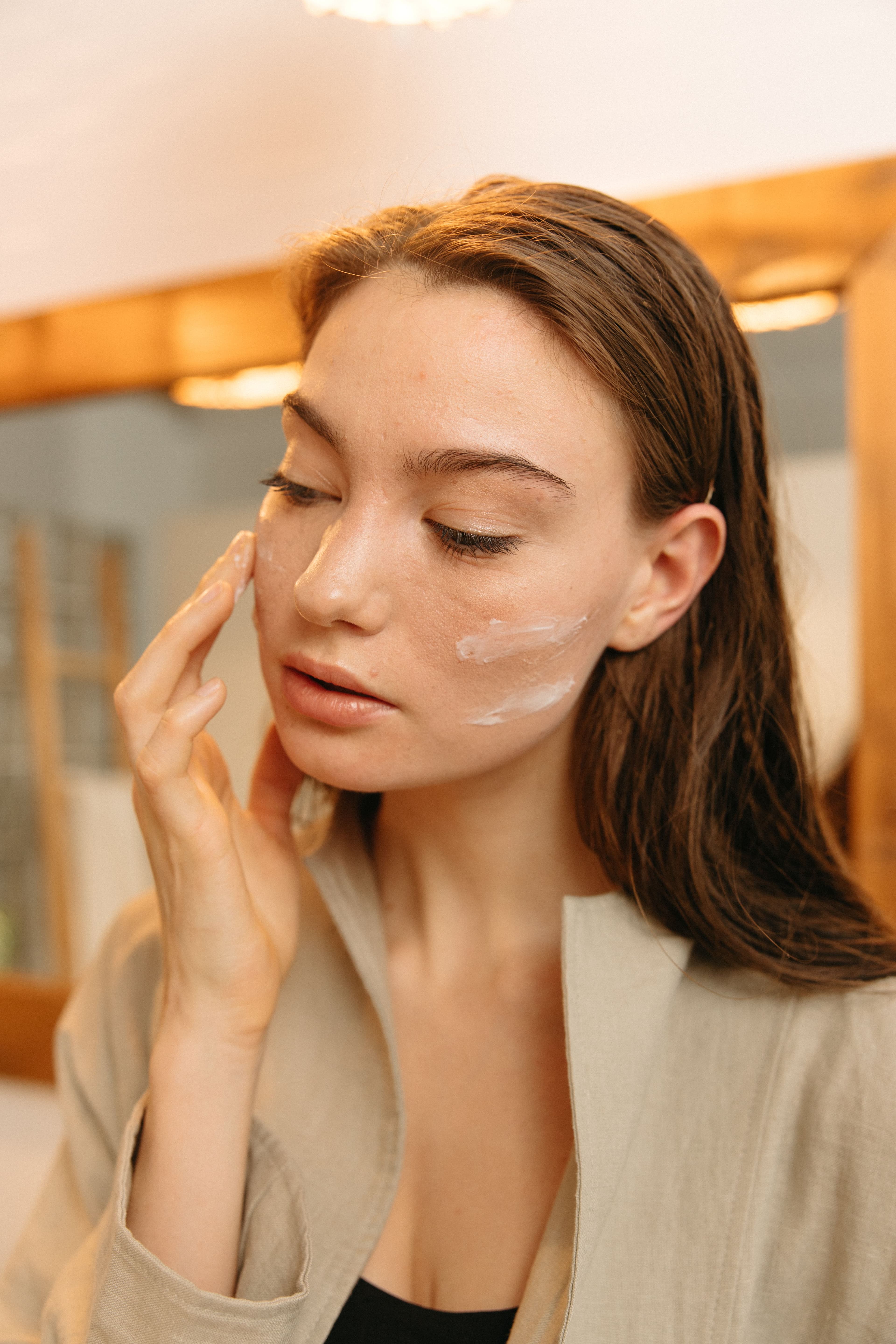 Woman looking at reflection in mirror and applying serum.