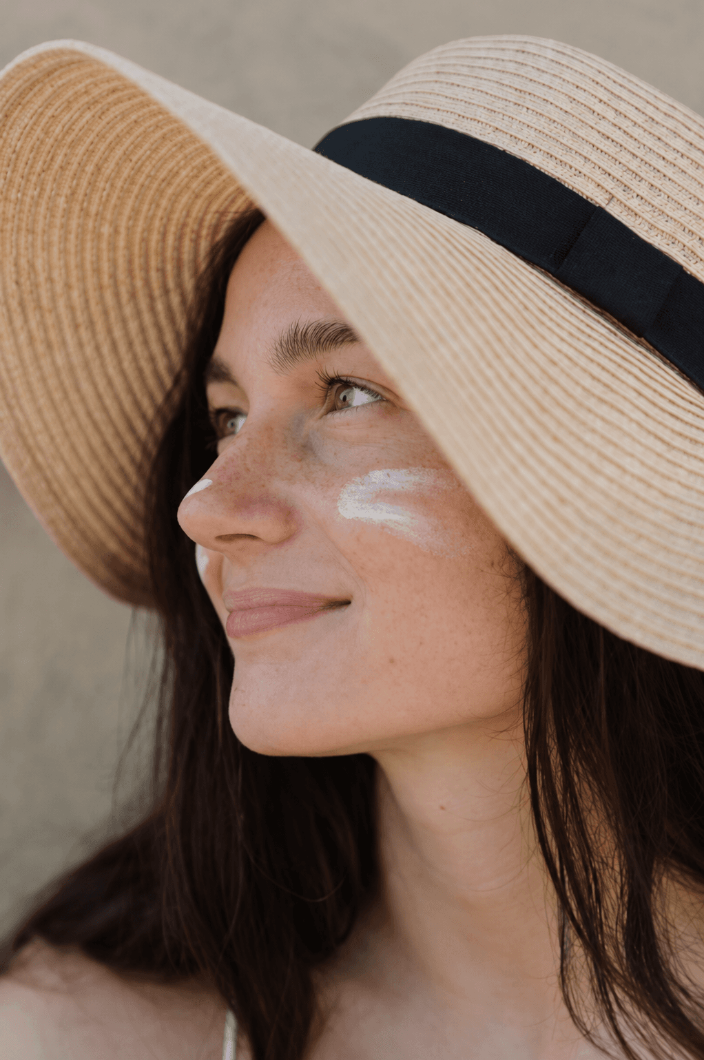 Woman in sunhat with sunscreen on her cheeks.