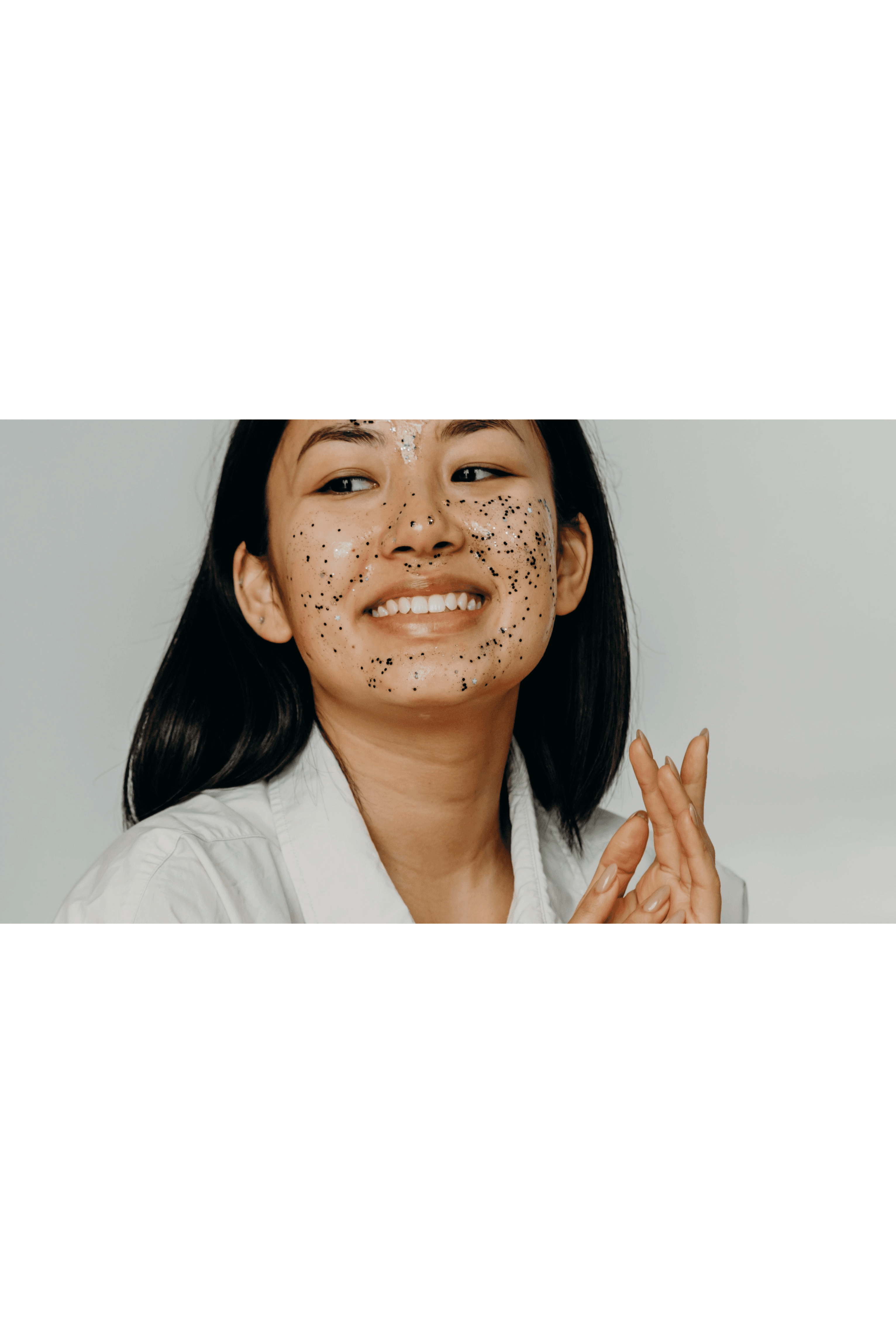Woman wearing unbuttoned white shirt with sparkly face mask is smiling.