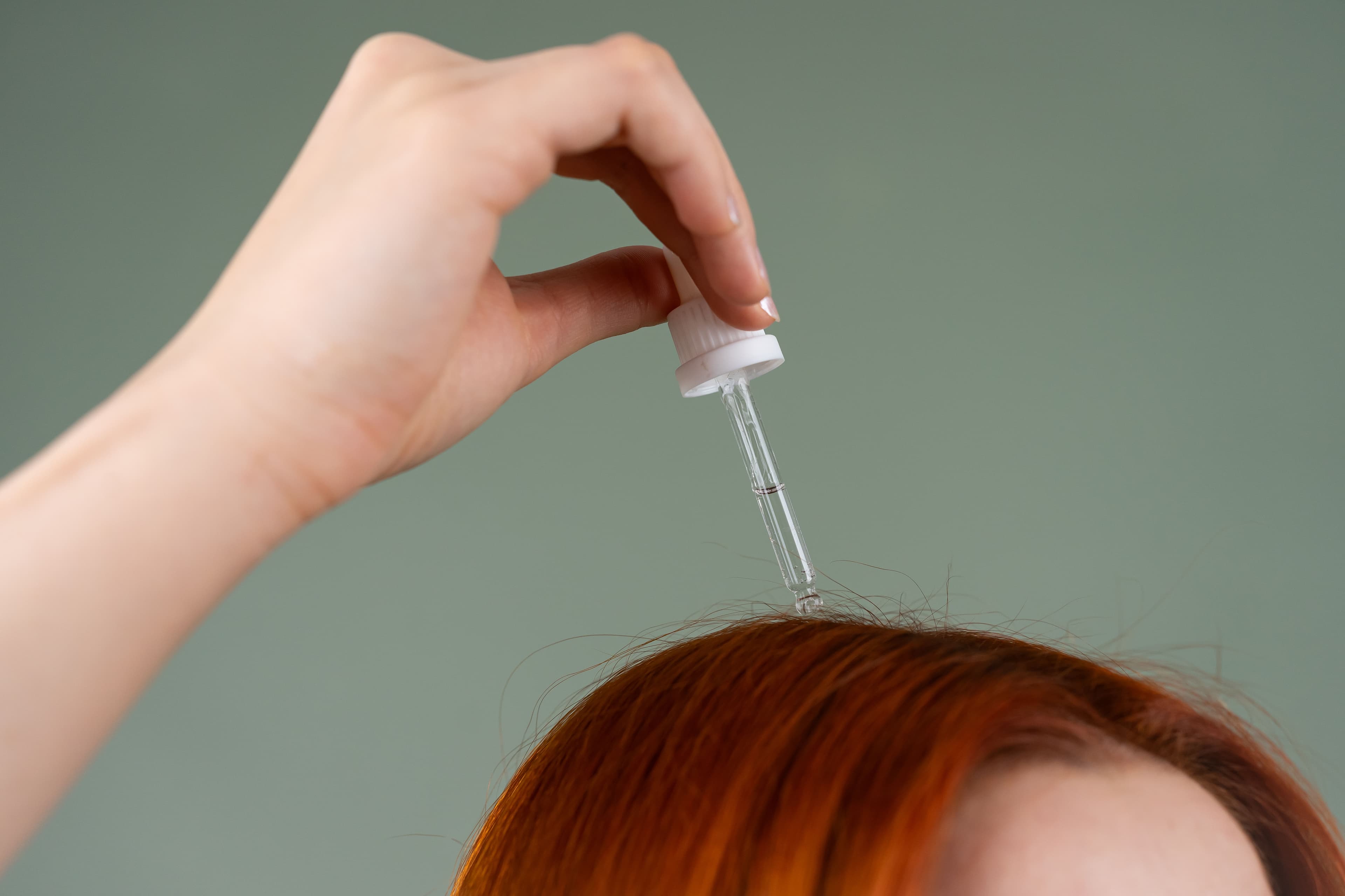 Person putting serum on scalp.