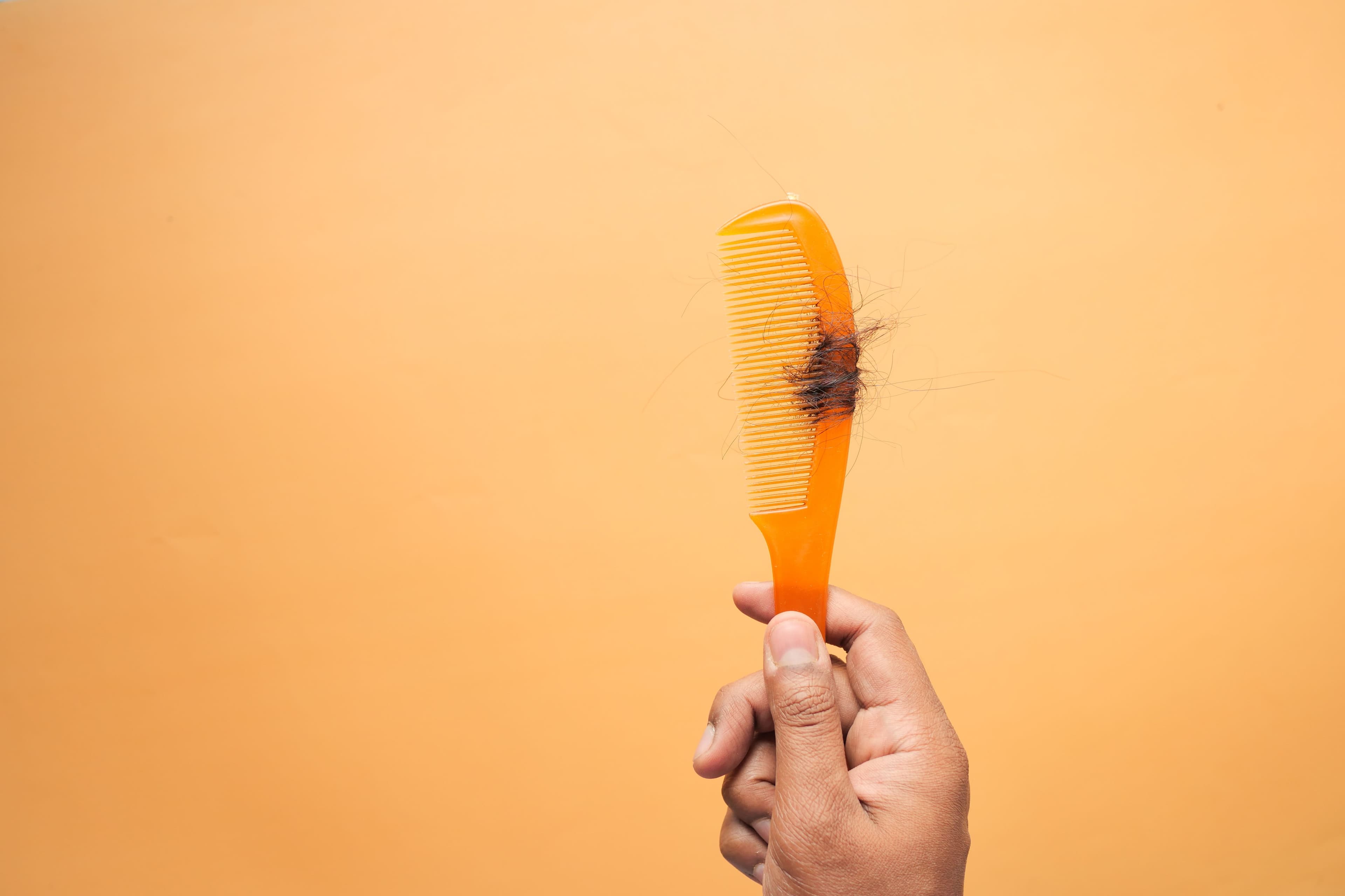 Orange comb with hair in it.